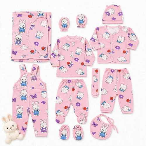 A coordinated baby clothing set laid out on a white background, including a pink long-sleeve top, matching pants, cardigan, hat, bib, booties, mittens, and overalls, all printed with white rabbits, purple butterflies, and small red/orange flower motifs. A
