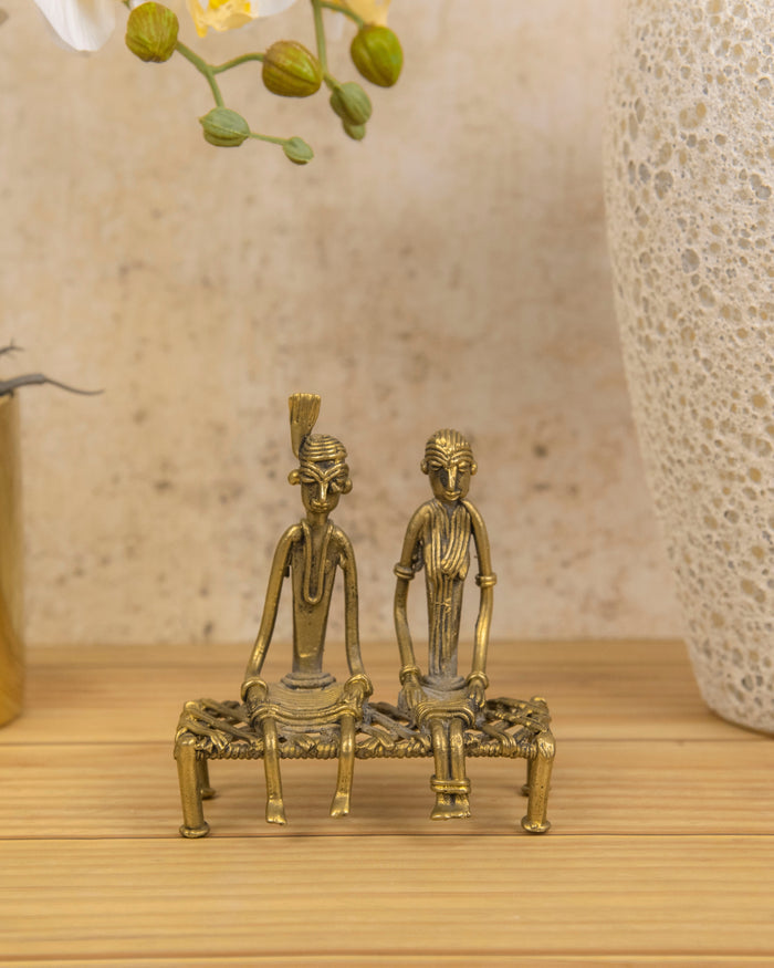 Brass tribal couple figurine, two seated figures on a charpoy