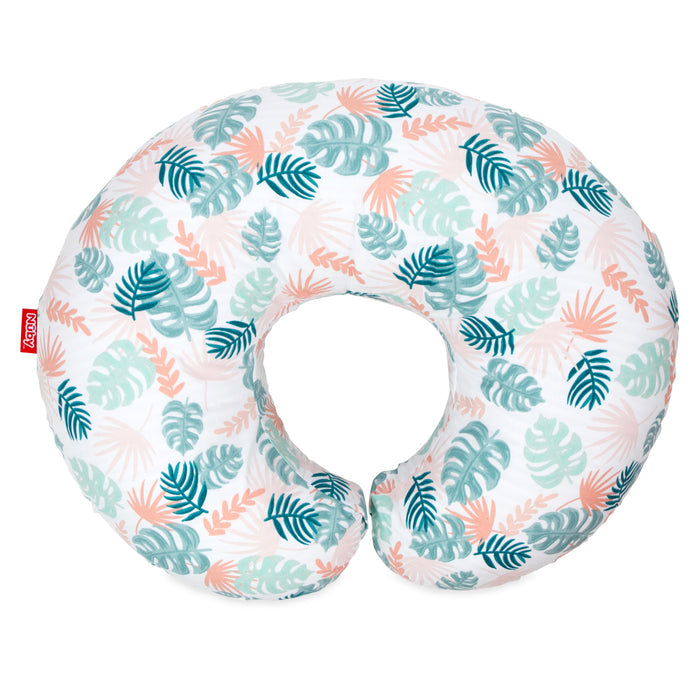 The Support Pod Feeding & Nursing Pillow with Cover features a crescent shape, white background, and a green, teal, and peach tropical leaf pattern. A small red tag with white text is attached to the seam.